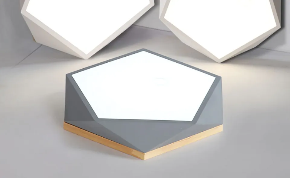 Geometryczna lampa stołowa: Nowoczesna lampa stołowa o geometrycznym, sześciokątnym kształcie z jasnym, oświetlonym panelem, otoczona podobnymi lampami