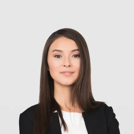 Portret kobiety z prostymi, długimi, ciemnymi włosami, ubranej w elegancką czarno-białą marynarkę. Ma spokojny wyraz twarzy, co sugeruje profesjonalny i pewny siebie charakter.
